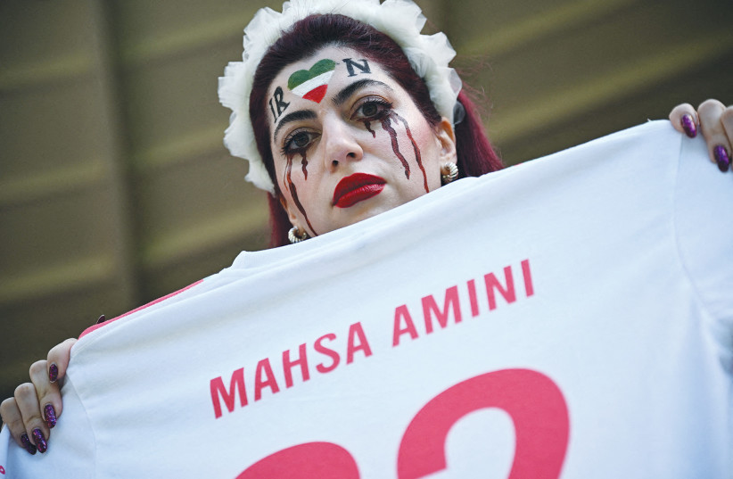  AN IRANIAN fan holds a jersey in memory of Mahsa Amini, inside the stadium before a World Cup soccer match between Iran and Wales, in Qatar, last November.  (credit: DYLAN MARTINEZ/REUTERS)