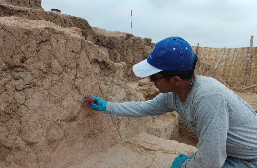 An archaeologist works on a 4,500-year-old polychrome wall, part of a temple belonging to the Late Preceramic period, in the Huaca Tomabal in the Valley of Viru, Peru August 24, 2023. (credit: Castillo/PAVI/Handout via REUTERS)