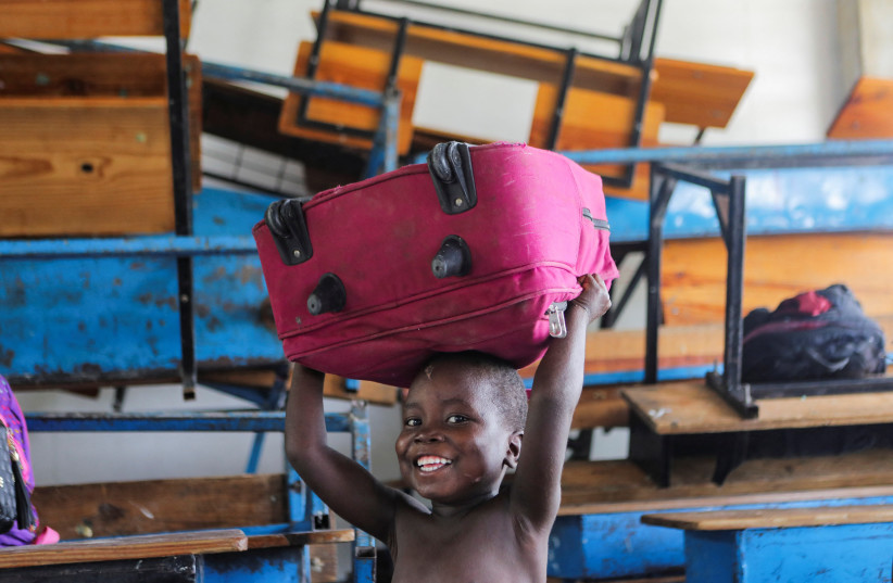  A young boy laughs while playing with a bag at a school, where he and others shelter after fleeing their neighbourhood Carrefour Feuilles when gangs took over, in Port-au-Prince, Haiti August 16, 2023. (credit: REUTERS/RALPH TEDY EROL)