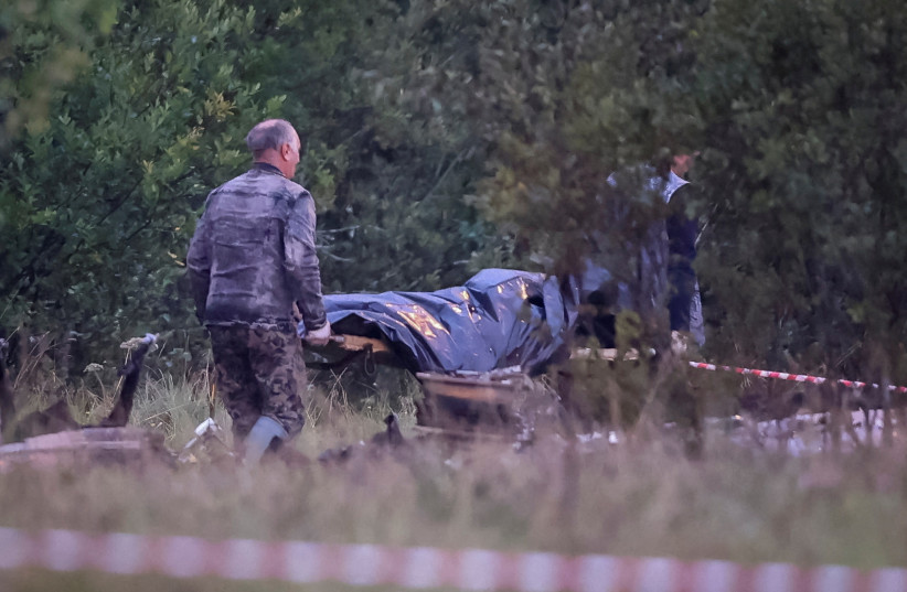 Emergency specialists carry a body bag near wreckages of the private jet linked to Wagner mercenary chief Yevgeny Prigozhin at the crash site in the Tver region, Russia, August 24, 2023. (credit: REUTERS/MARINA LYSTSEVA)