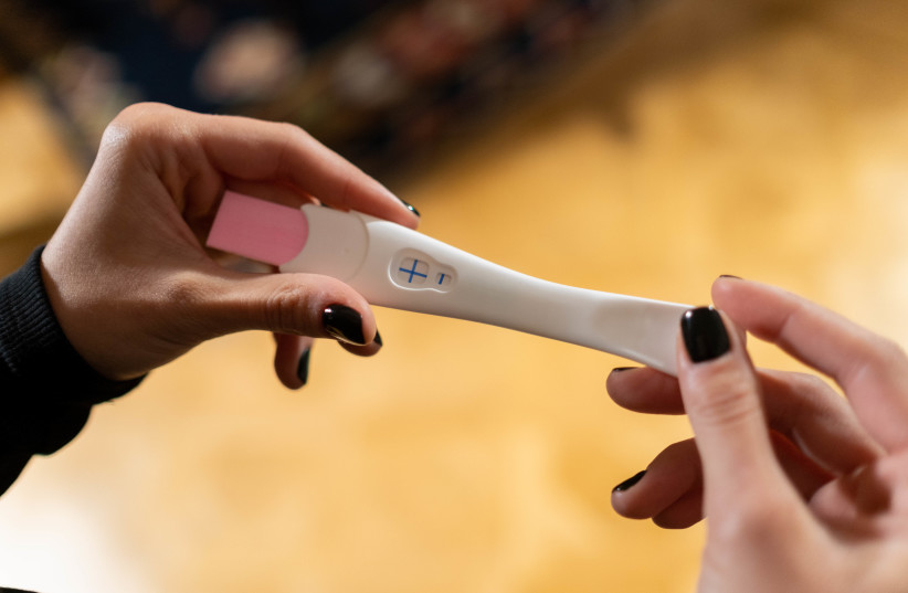  A woman holds a pregnancy test in her hands. (credit: PEXELS)