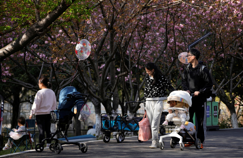  A parents pushes a stroller with a baby in a park in Shanghai, China, April 2, 2023. (credit: REUTERS/ALY SONG)