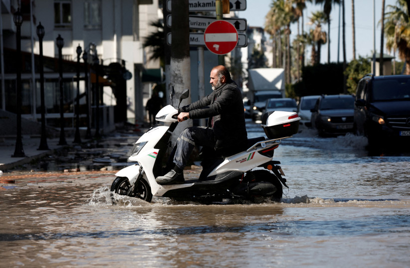  A man rides his scooter on a street flooded by sea water on a coastal road following a deadly earthquake in Iskenderun, Turkey, February 9, 2023. (credit: BENOIT TESSIER/REUTERS)