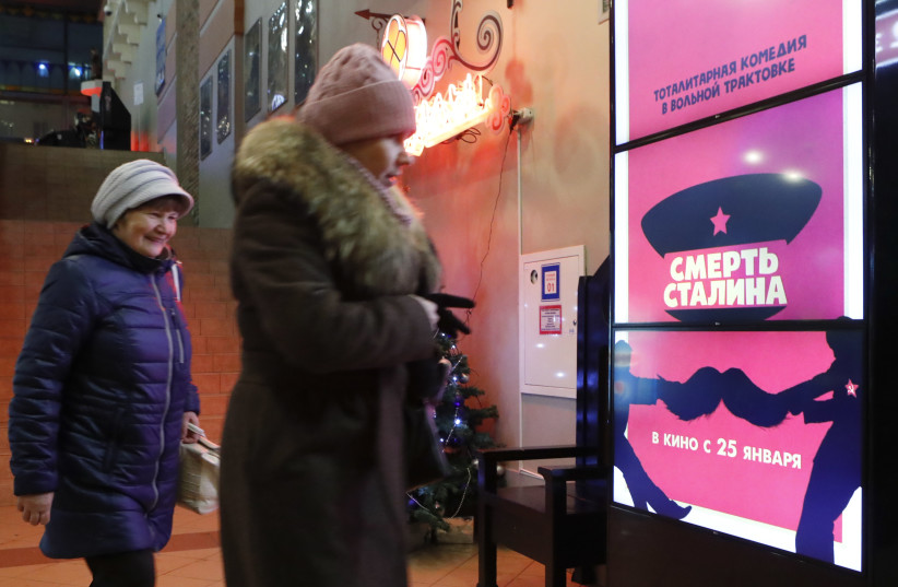 People walk past a poster of the movie ''Death of Stalin'' at a cinema in Moscow, Russia January 23, 2018. Picture taken January 22, 2018. (credit: SERGEI KARPUKHIN/REUTERS)