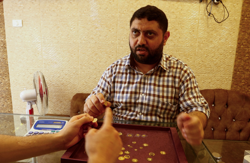 Palestinian customer Adel AL-Rafati buys gold coins made for low-income residents seeking savings, in Gaza City August 27, 2023 (credit: IBRAHEEM ABU MUSTAFA/REUTERS)