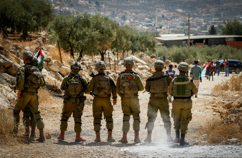  Israeli soldiers stand guard while Palestinians and left wing activists protest in the village of Beit Dajan, in the West Bank, on September 8, 2023 (credit: NASSER ISHTAYEH/FLASH90)