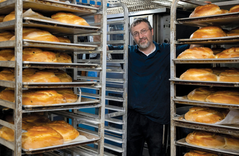  Israel Roling, the owner of Roling’s Bakery, stands between hundreds of loaves of ‘challah’ prepared for Rosh Hashanah in Elkins Park, Pennsylvania. (credit: RACHEL WISNIEWSKI/REUTERS)
