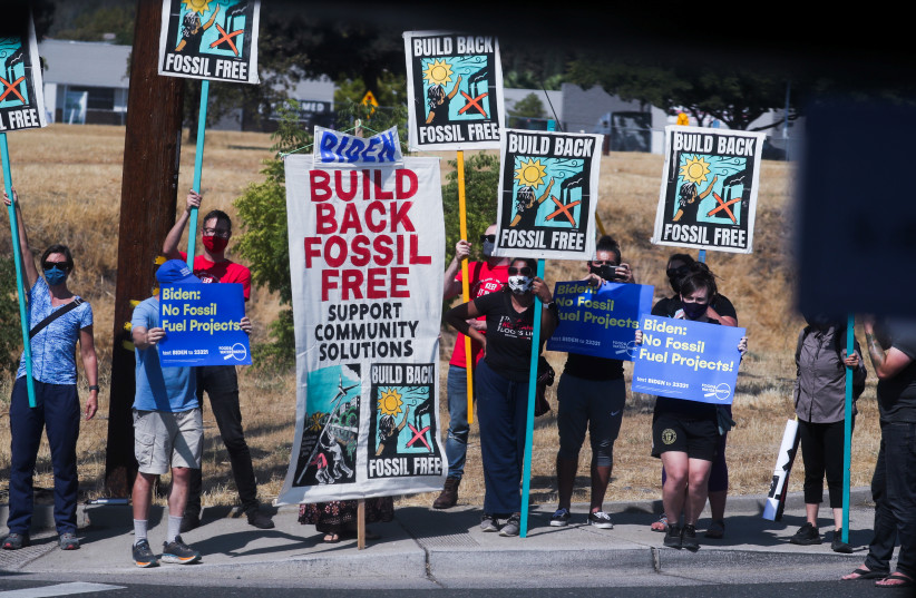 Protesters against fossil fuel hold signs along a road as U.S. President Joe Biden visits Mather, California, U.S., September 13, 2021. (credit: LEAH MILLIS/REUTERS)