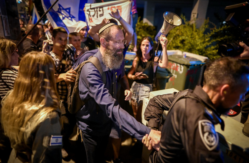 Rabbi Yigal Levinstein is seen being escorted by police as he is surrounded by protesters, in Tel Aviv, on September 19, 2023. (credit: AVSHALOM SASSONI/FLASH90)