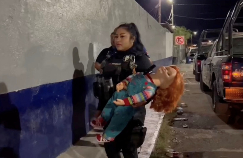 A police officer holds the handcuffed ''demon doll'' Chucky after arresting Carlos ''N'', a man who used the doll with a knife to rob people, according to local media, in Monclova, Mexico, September 11, 2023, in this screen grab obtained from a handout video. (credit: Noticias NRT Mexico/Handout via REUTERS)