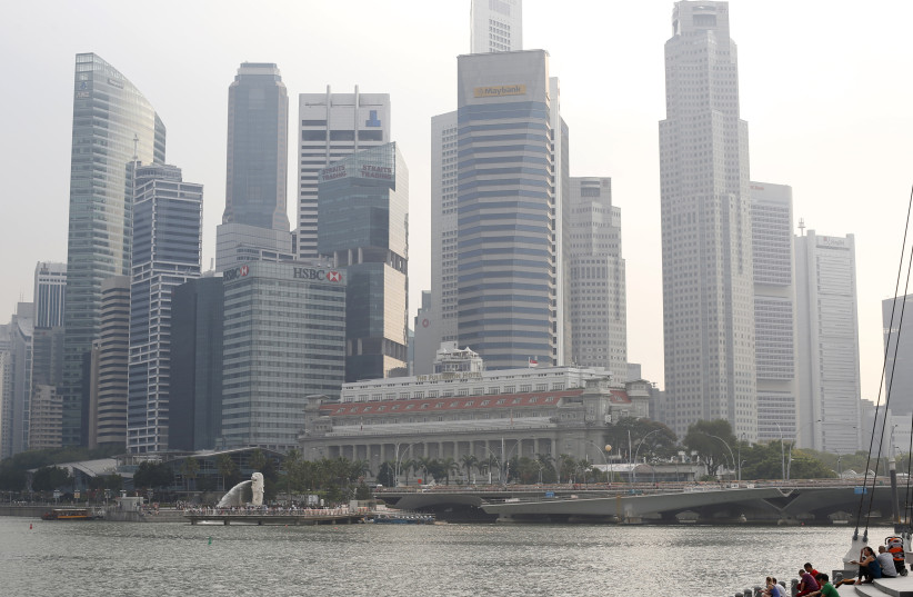  People sit along the Marina Bay area in the hazy skyline of Singapore March 4, 2014 (credit: REUTERS/EDGAR SU)