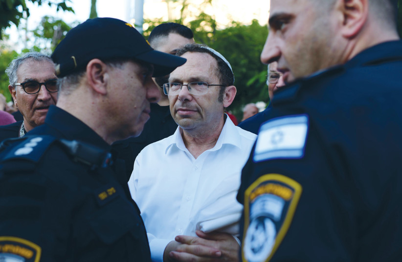 POLICE STAND guard as Rosh Yehudi head Rabbi Israel Zeira (center) looks on, at the onset of Yom Kippur, in Dizengoff Square in Tel Aviv, where the organization placed a partition between men and women for prayers.