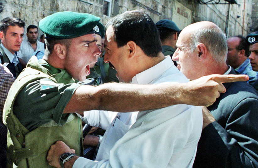  An Israeli policeman argues with a Palestinian man on October 13, 2000 in Jerusalem during the Second Intifada. (credit: Amit Shabi/Reuters)