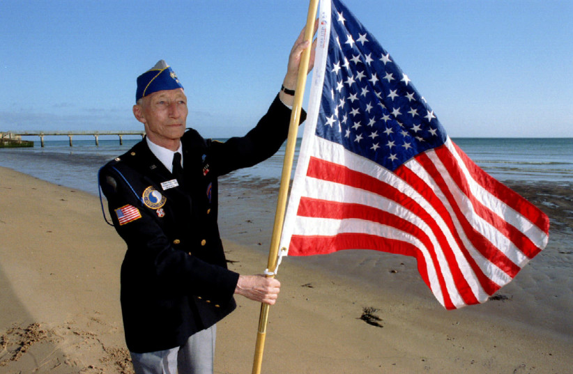 Dutch WWII veteran Robert Wynoogst, 68, who landed in Normandy with the US 29th infantry division on 6th June1944, plants an American flag in the sand on Omaha Beach, June3 (credit: REUTERS)