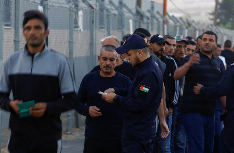  A Palestinian police officer checks the documents of Palestinian workers as they enter the reopened Erez crossing to Israel, after Israeli ends a ban on workers from Gaza, in Gaza City September 28, 2023. (credit: REUTERS/IBRAHEEM ABU MUSTAFA)