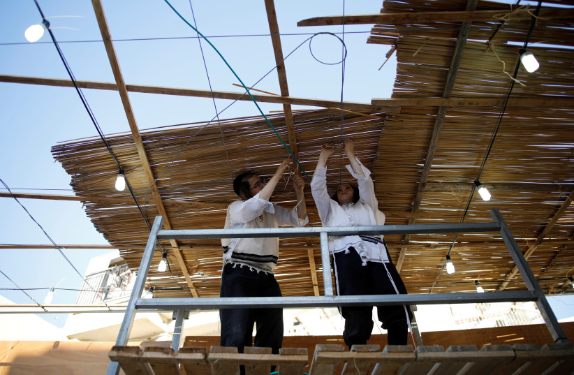 Ultra-Orthodox Jewish men build a ritual booth, known as a sukkah, used during the Jewish holiday of Sukkot, in Ashdod, Israel September 20, 2018. (credit: REUTERS/AMIR COHEN)