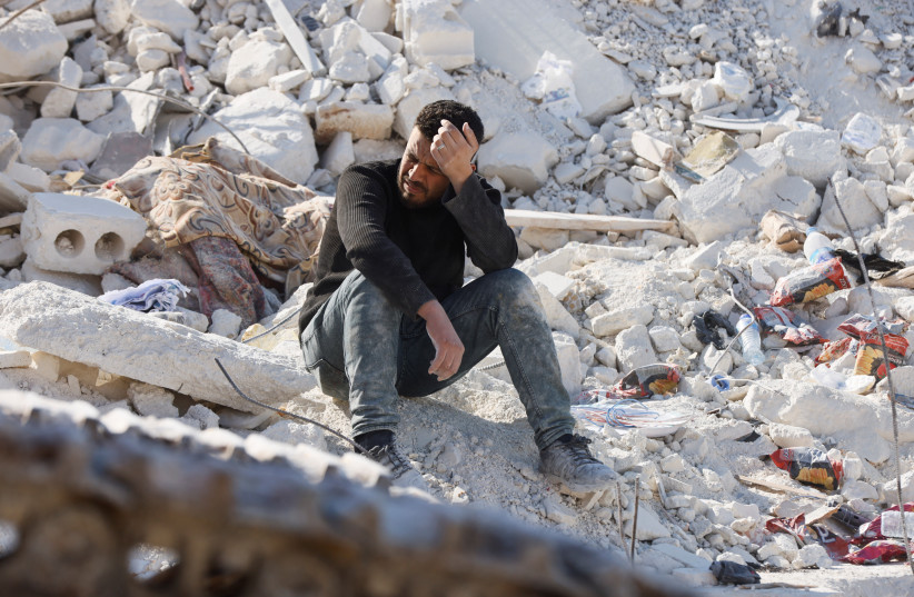  A man sits atop the ruins of a home where his relatives once lived in the aftermath of a deadly earthquake in the rebel-held town of Harem, in Idlib governorate, Syria, February 14, 2023. (credit: REUTERS/EMILIE MADI)