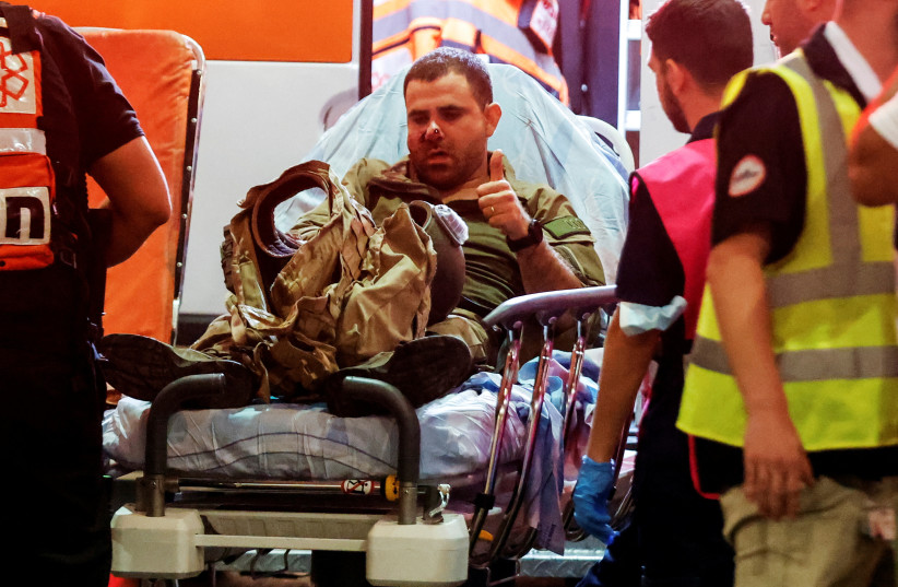  An injured Israeli officer gestures as he arrives at a hospital, following a mass-infiltration by Hamas gunmen from the Gaza Strip, in Ashkelon, southern Israel (credit: AMIR COHEN)