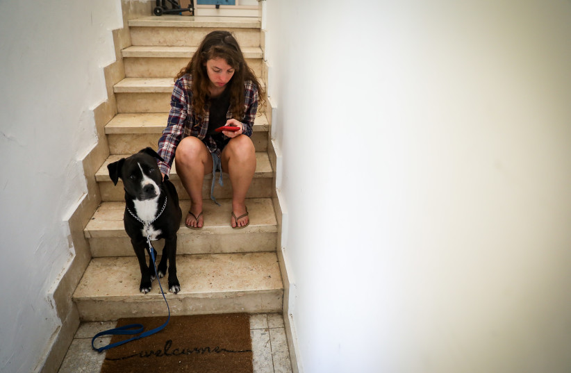  A woman and her dog takes cover in a stairway in Jerusalem, as a red Siren alert is sounded, when a rocket barrage is fired from Gaza into Israel, October 7, 2023.  (credit: NOAM REVKIN FENTON/FLASH90)