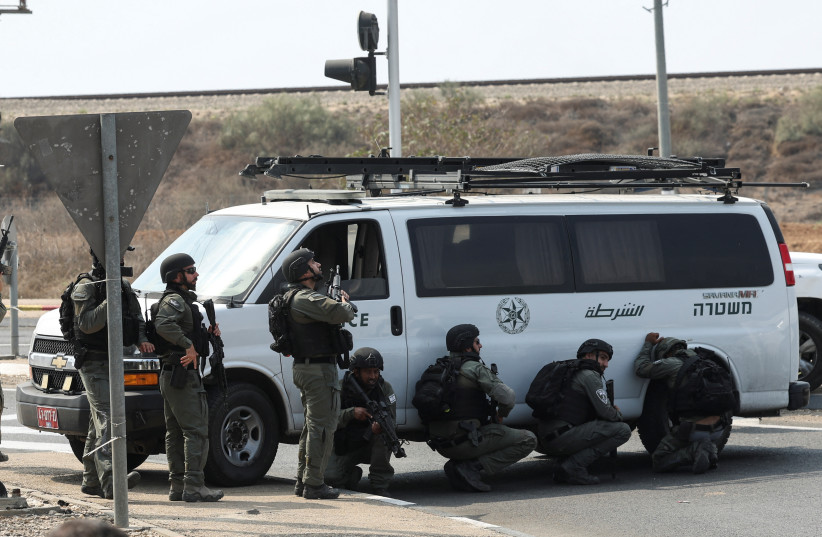 Israeli border police take cover by a vehicle following a mass infiltration by Hamas by Hamas terrorists from the Gaza Strip, near Sderot in southern Israel October 8, 2023 (credit: RONEN ZVULUN/REUTERS)