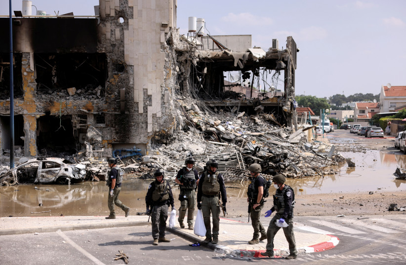 Israeli security gather near a rifle at the site of a battle following a mass infiltration by Hamas terrorists from the Gaza Strip, in Sderot, southern Israel October 8, 2023 (credit: RONEN ZVULUN/REUTERS)