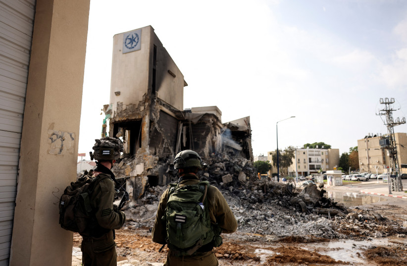  Israeli soldiers look at the remains of a police station which was the site of a battle following a mass infiltration by Hamas gunmen from the Gaza Strip, in Sderot, southern Israel October 8, 2023.  (credit: REUTERS/Ronen Zvulun)