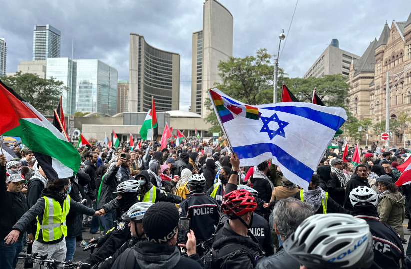  People carry Palestinian flags near an Israeli flag of a counter-protester during a rally in front of City Hall in Toronto, Ontario, Canada October 9, 2023. (credit: REUTERS/Kyaw Soe Oo)