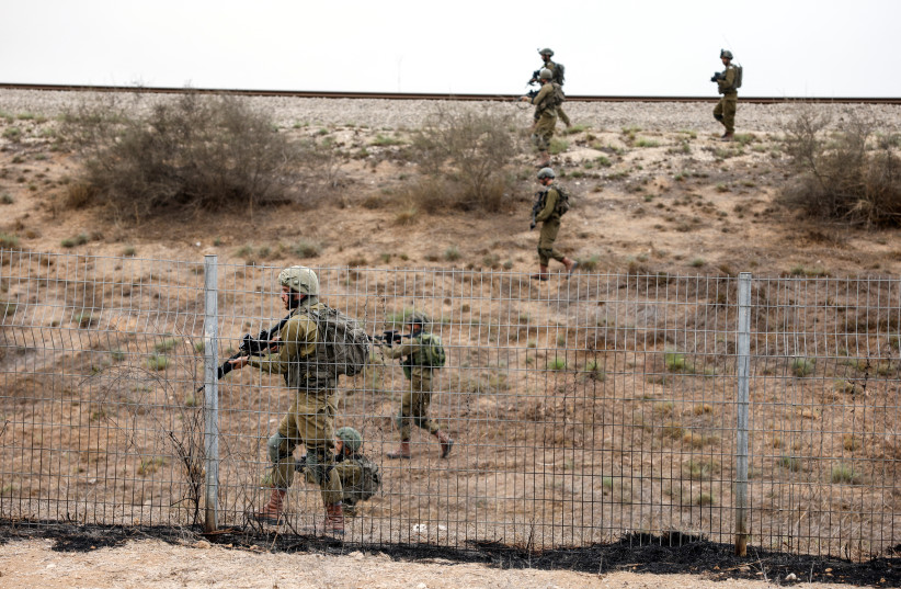 Israeli soldiers scan an area while sirens sound as rockets from Gaza are launched towards Israel, near Sderot, southern Israel, October 9, 2023