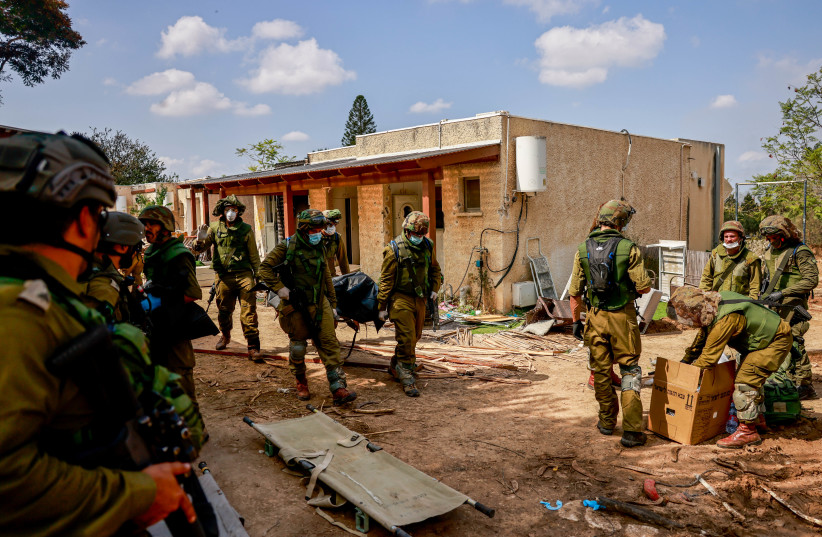  Israeli soldiers around the destruction caused by Hamas Militants in Kibbutz Kfar Aza, near the Israeli-Gaza border, in southern Israel, October 10, 2023. (credit: Chaim Goldberg/Flash90)