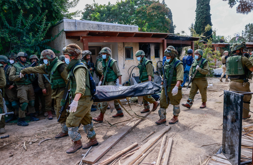  Israeli soldiers remove bodies of of Israeli civilians in Kibbutz Kfar Aza, near the Israeli-Gaza border, in southern Israel, October 10, 2023. (credit: CHAIM GOLDBEG/FLASH90)