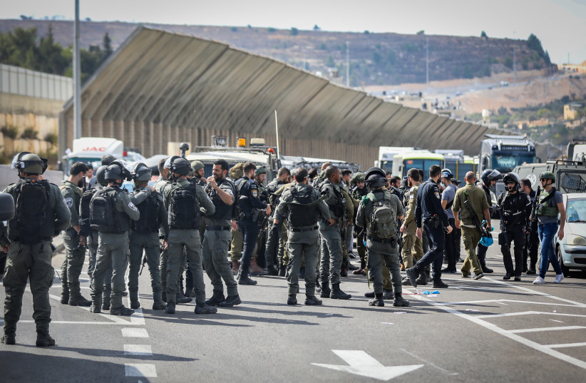 Police and security personnel gather around the body of a Palestinian terrorist at the scene of a shooting attack at ''HaMinharot'' checkpoint, near Jerusalem, October 11, 2023. (credit: NOAM REVKIN FENTON/FLASH90)