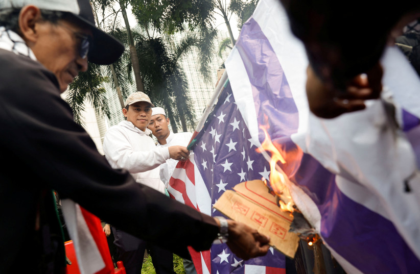 Pro-Palestinian supporters set fire on banners depicting U.S. and Israeli flags, during a rally calling for an end to the ongoing conflict between Israel and the Palestinian Islamist group Hamas, outside the U.S. Embassy in Jakarta, Indonesia, October 11, 2023. (credit: REUTERS/WILLY KURNIAWAN)
