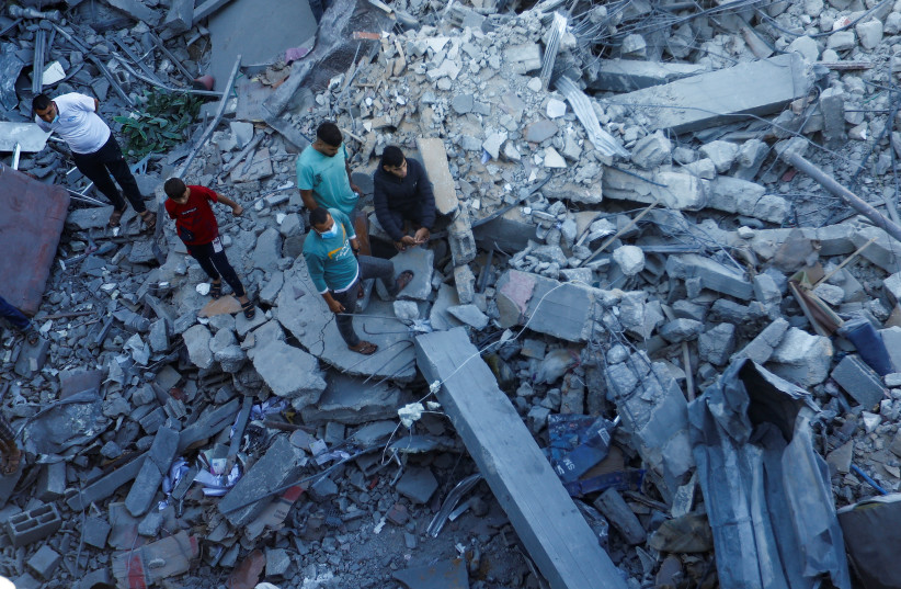  Palestinians search for casualties under the rubble in the aftermath of Israeli strikes amid the ongoing conflict between Israel and the Palestinian Islamist group Hamas, in Khan Younis in the southern Gaza Strip October 13, 2023. (credit: REUTERS/IBRAHEEM ABU MUSTAFA)