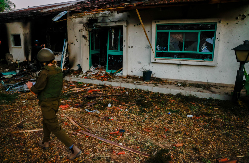  A SOLDIER passes in front of a burned home in Kibbutz Be’eri, whose family occupants were slaughtered by Hamas terrorists on Saturday. (credit: Chaim Goldberg/Flash90)