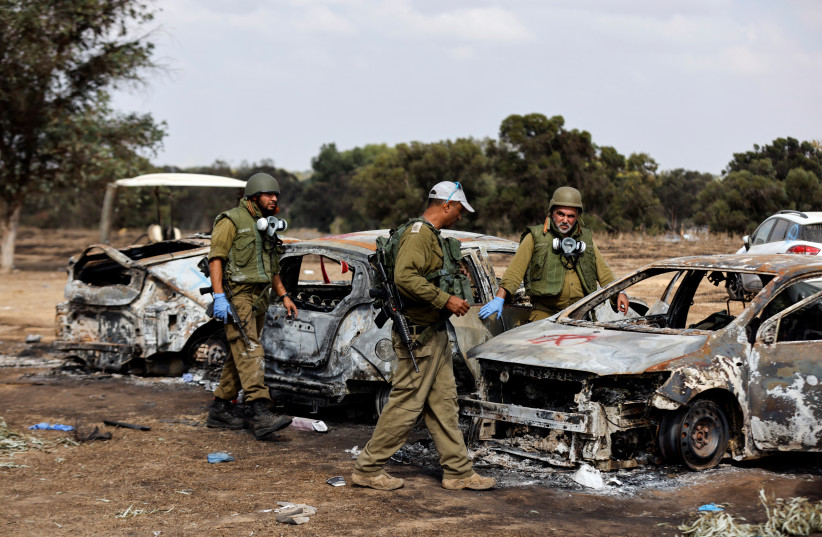  Israeli soldiers inspect the burnt cars of festival-goers at the site of an attack on the Nova Festival by Hamas gunmen from Gaza, near Israel's border with the Gaza Strip, in southern Israel, October 13, 2023.  (credit: REUTERS/AMIR COHEN)