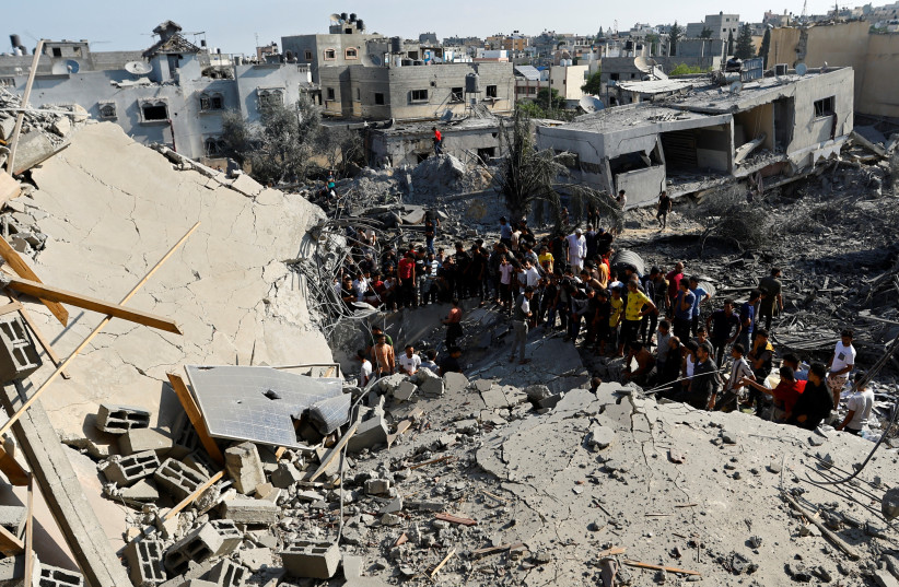  Palestinians gather near the rubble in the aftermath of Israeli strikes, in Khan Younis in the southern Gaza Strip, October 14, 2023. (credit:  REUTERS/Ibraheem Abu Mustafa)
