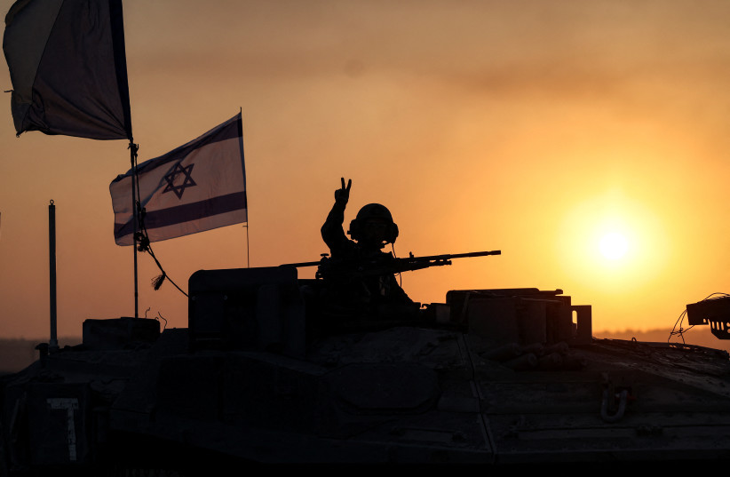  An Israeli soldier looks out from a tank at sunset as an artillery unit gathers near Israel's border with the Gaza Strip, in southern Israel, October 12, 2023.  (credit: REUTERS/Ronen Zvulun)
