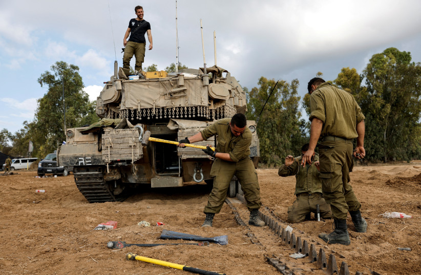  Israeli soldiers walk next to an Armoured Personnel Carrier (APC) near Israel's border with the Gaza Strip, in southern Israel October 15, 2023. (credit: REUTERS/Ronen Zvulun)