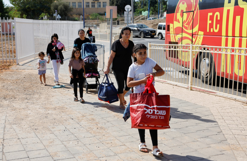 People walk with their belongings next to a bus as Israelis are evacuated from the southern town of Sderot, near Israel's border with Gaza, October 15, 2023. (credit: REUTERS/AMIR COHEN)