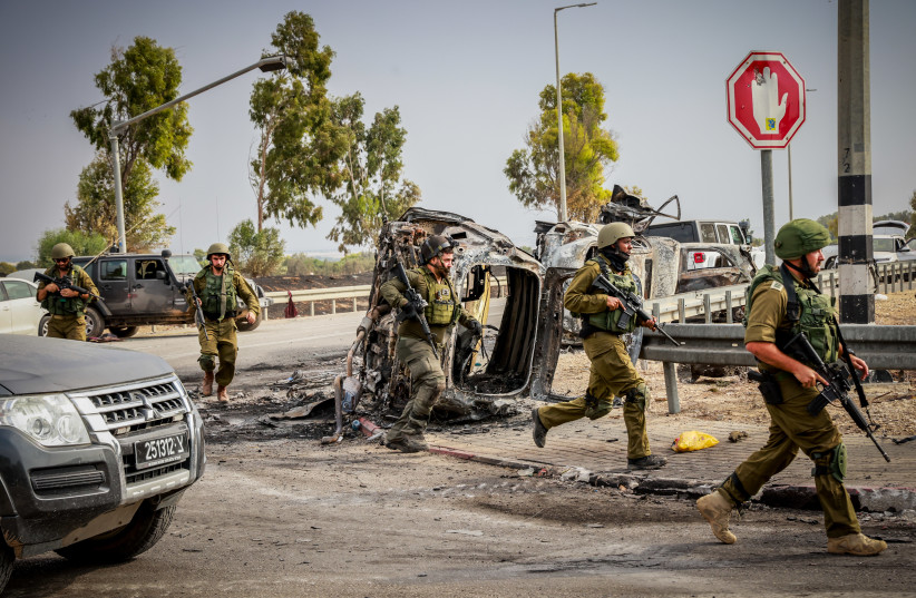  Israeli soldiers seen next to burnt cars at the entrance to Kibbutz Be'eri, near the Israeli-Gaza Border, southern Israel, October 9, 2023. (credit: YOSSI ZAMIR/FLASH90)