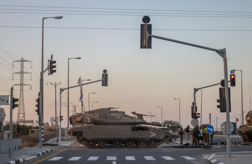  AN IDF tank crosses a main road near the border with Gaza. (credit: CHAIM GOLDBEG/FLASH90)