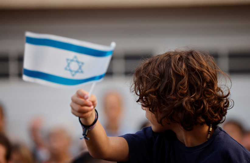  A kid holds an Israeli flag to protest about the conflict between Israel and Hamas, in Brussels, Belgium, October 9, 2023.  (credit: REUTERS/Johanna Geron)