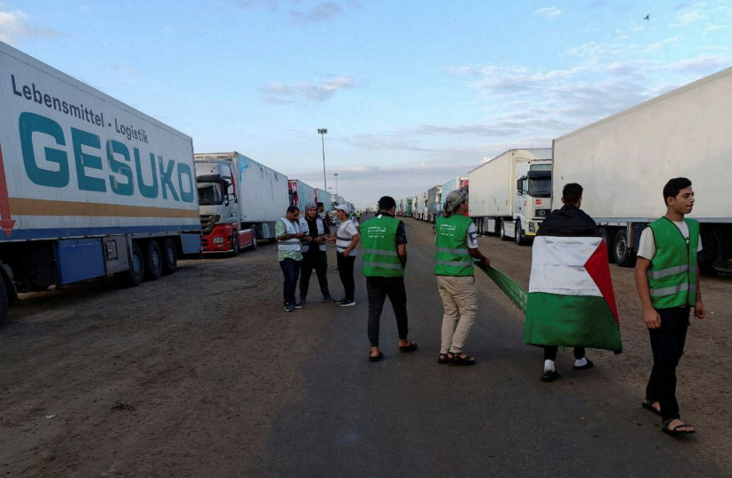  Egyptian volunteers gather with a Palestinian flag next to a truck convoy carrying humanitarian aid from Egyptian NGOs for Palestinians at the Rafah crossing, waiting for a decision for it to open, to enter Gaza, amid the ongoing conflict between Israel and the Palestinian Islamist group Hamas. (credit: REUTERS/STRINGER)