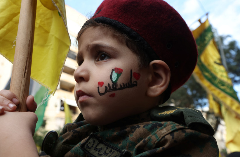 A boy holds a flag as Hezbollah supporters attend a protest, after hundreds of Palestinians were killed in a blast at Al-Ahli hospital in Gaza that Israeli and Palestinian officials blamed on each other, in Beirut's southern suburbs, Lebanon October 18, 2023. (credit: REUTERS/MOHAMED AZAKIR)