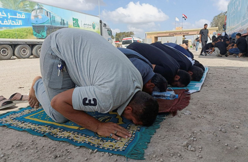  Egyptian truck drivers pray in front of the Rafah crossing, as trucks carrying humanitarian aid for Palestinians await a decision for it to open to enter Gaza, amid the ongoing conflict between Israel and the Palestinian Islamist group Hamas, in Rafah, Egypt October 18, 2023. (credit: STRINGER/ REUTERS)