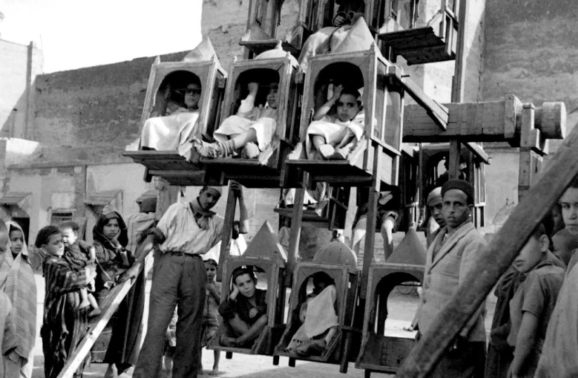  Children sit in a kind of Ferris wheel, in April 1946 in the Mellah, the Jewish quarter of Marrakesh. (credit: Manuel and Landry Gautier)