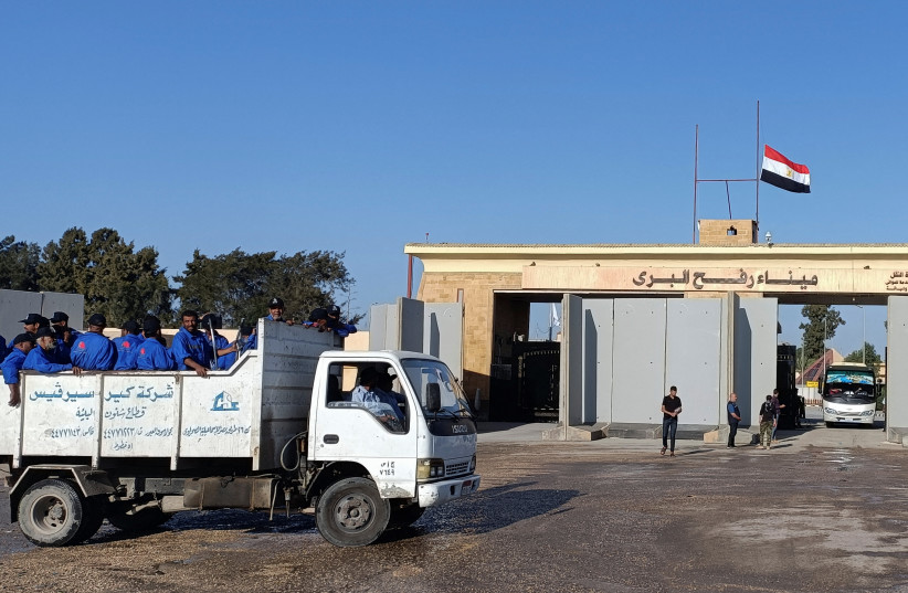 Egyptian cleaning workers are seen in front of the Rafah crossing from the Egyptian side, while trucks carrying humanitarian aid for Palestinians await for it to open to enter Gaza, amid the ongoing conflict between Israel and the Palestinian terrorist group Hamas, in Rafah, Egypt October 19, 2023. (credit: REUTERS/STRINGER)