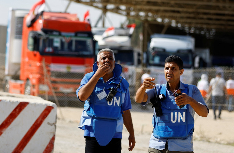 UN workers gesture as trucks carrying aid arrive at the Palestinian side of the border with Egypt, as the conflict between Israel and Palestinian terrorist group Hamas continues, in Rafah in the southern Gaza Strip, October 21, 2023. (REUTERS/Ibraheem Abu Mustafa)