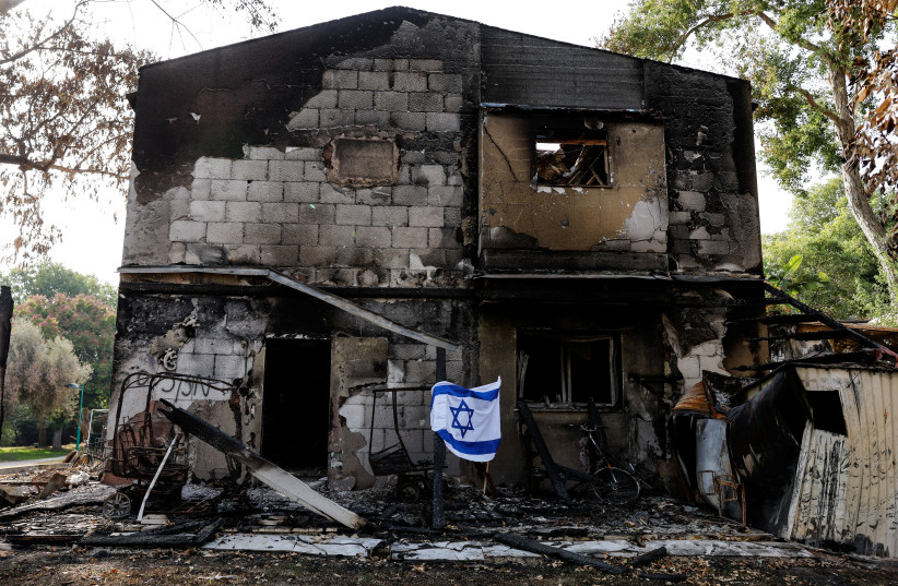 An Israeli flag flutters in front of the remains of a building, following a deadly infiltration by Hamas gunmen from the Gaza Strip, in Kibbutz Beeri in southern Israel October 22, 2023 (credit: AMIR COHEN/REUTERS)