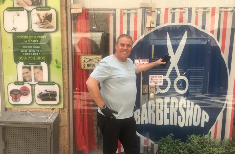 Eli Aroes in front on his barber shop.